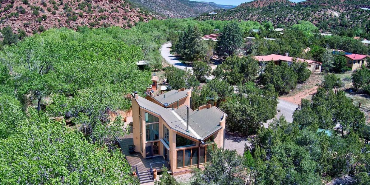 Modern house surrounded by lush trees in a mountainous area.