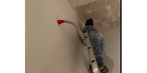 taping ceiling corners to prepare for a fresh coat of paint.