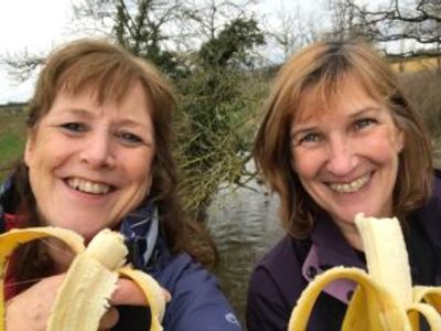 Two women, eating bananas.