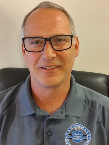 Smiling man wearing glasses and a professional polo shirt.