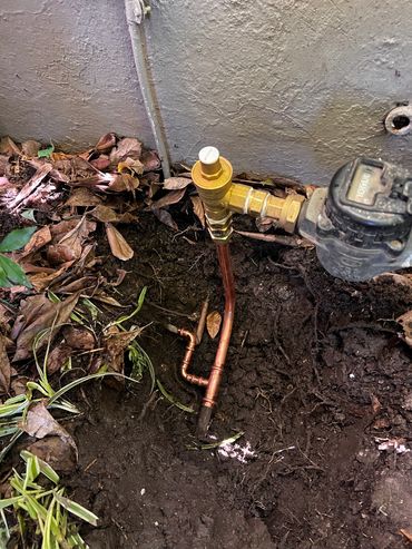 Newly installed outdoor copper water pipe with valve and meter.