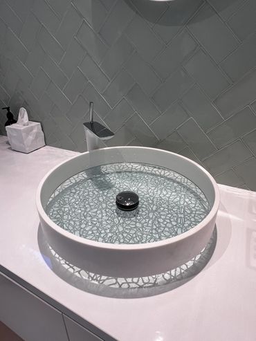 Modern round bathroom sink with decorative bottom and sleek faucet.
