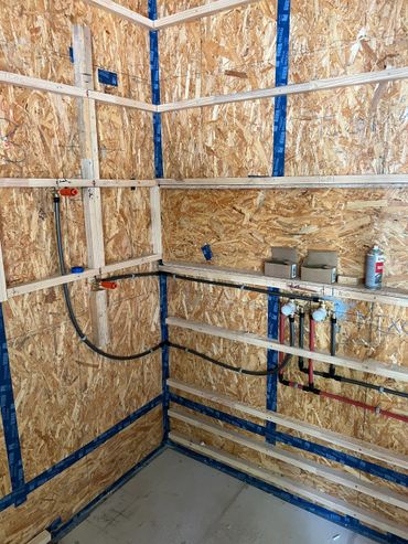 Plumbing and framing work in progress inside a wooden stud wall corner.