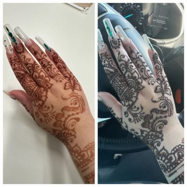 Henna-decorated hand with long acrylic nails and green gems.