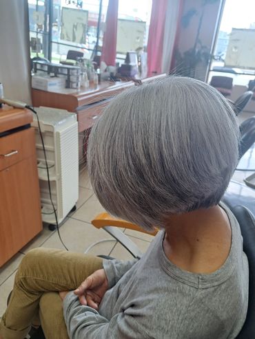 Person with freshly cut short grey hair in a salon.