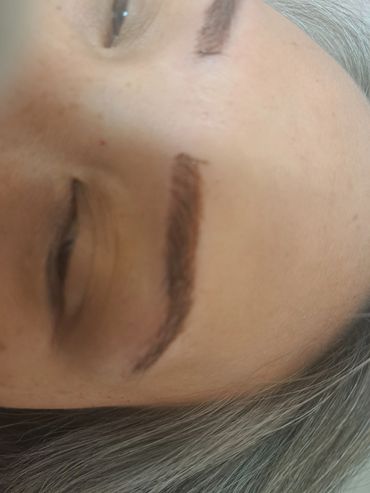 Close-up of a person's eye and eyebrow with silver hair.