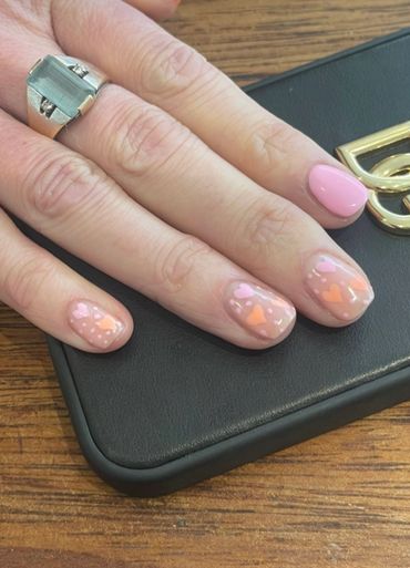 Hand with pastel heart-themed nail art and a silver ring.