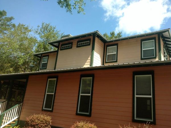 Two-story house with peach and cream siding under a clear blue sky.