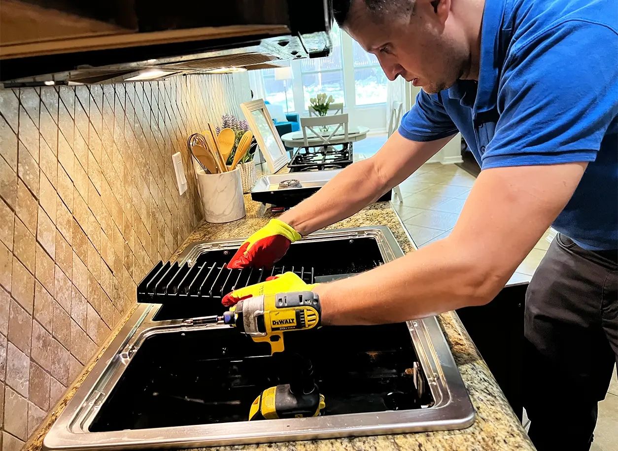 Technician diagnosing a built-in gas cooktop during appliance repair service in Austin, TX