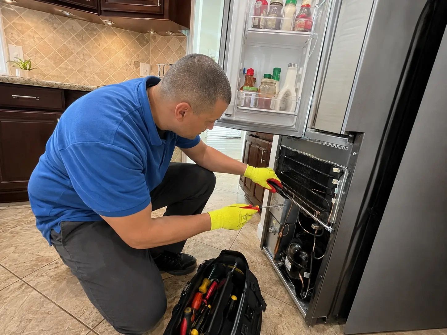 Technician repairing a refrigerator in a home kitchen in Austin, TX