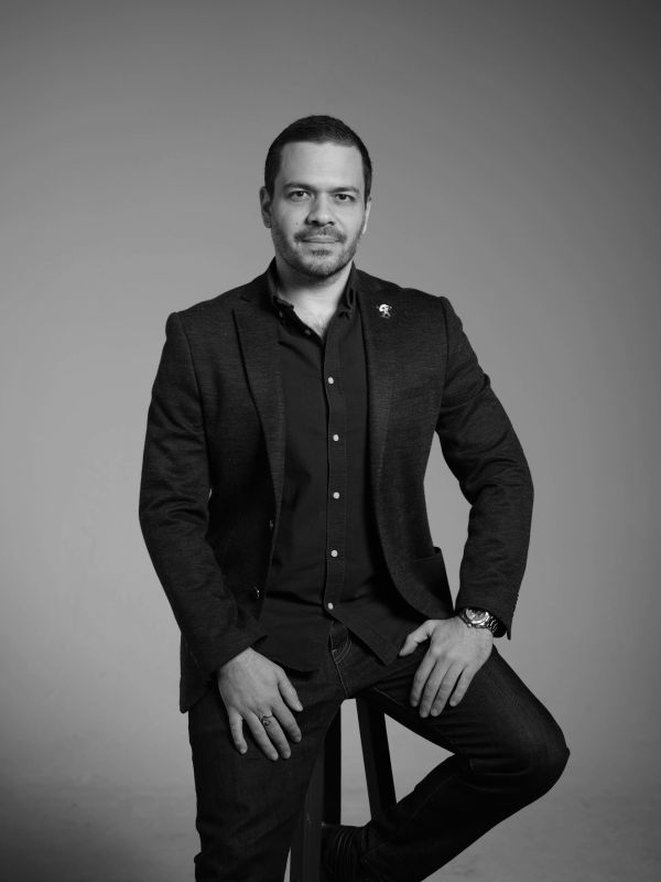 Black and white portrait of a man in a blazer with a confident expression.