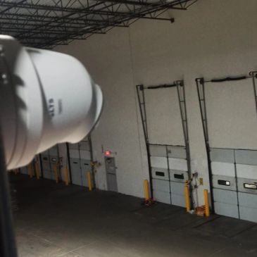 Interior de un almacén con puertas de carga y cámara de seguridad.