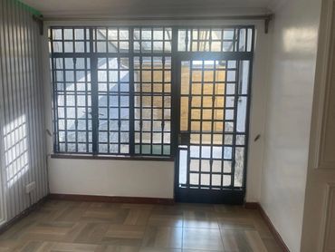 Empty room with tiled floor and barred window door combination.