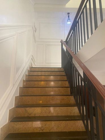 Indoor staircase with polished brown steps and a black railing.