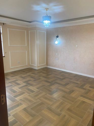 Empty room with wooden patterned floor and modern lighting fixtures.