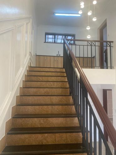 Indoor staircase with brown steps and black railing under modern lighting.