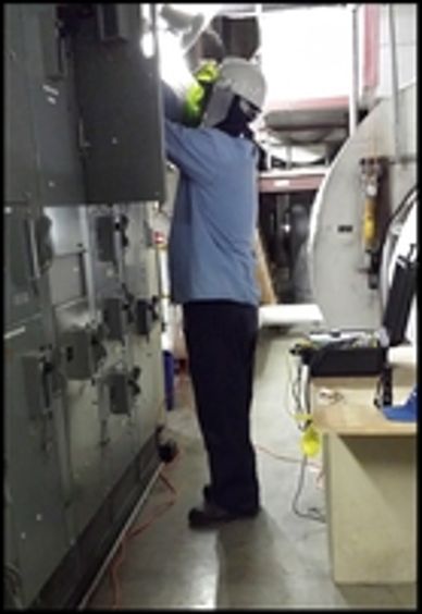 Technician testing electric motors at motor control cabinet