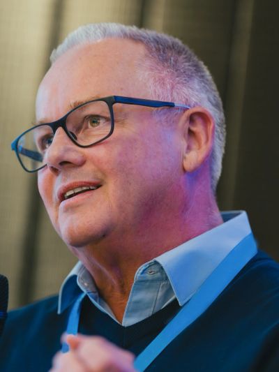 Simon Kear speaking at a conference in 2025.