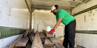 Green Source Junk Removal employee loading wood on to truck.