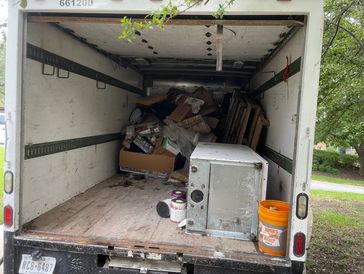 Picture shows a refrigerator and miscellaneous junk inside green source junk removal's truck.