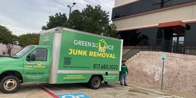 Green Source Junk Removal truck parked in front of commercial building.