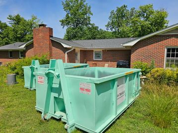 Two 10-Yard green dumpsters in a yard
