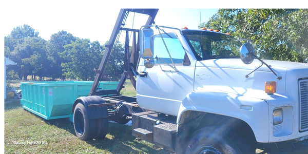 15-Yard dumpster being dropped off from a white roll-off truck