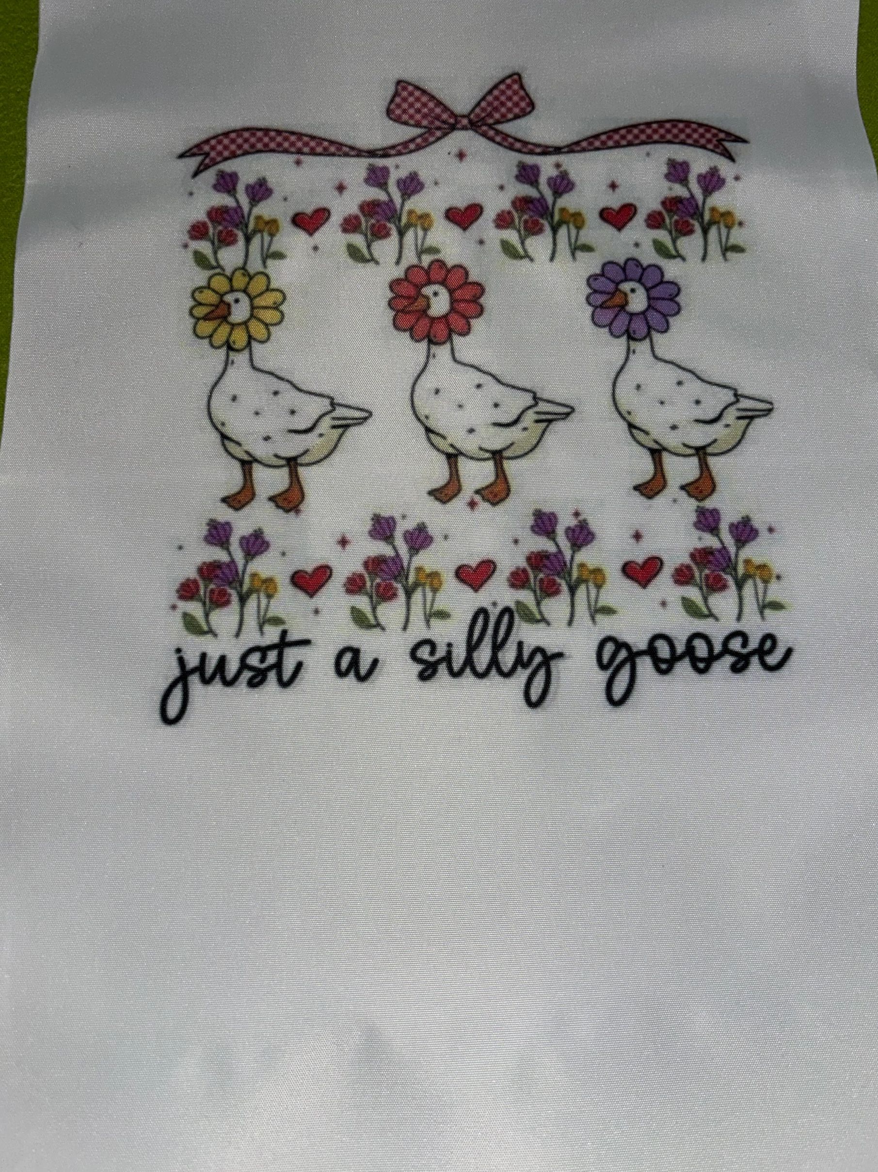 Cute illustration of geese with flower heads and the phrase 'just a silly goose'.