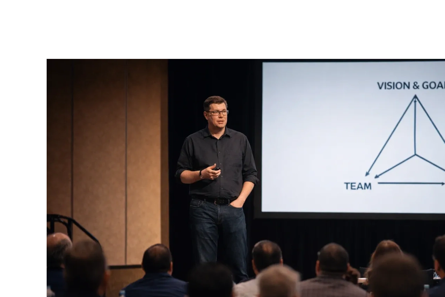 Man giving a presentation on vision, goals, and team to an audience.