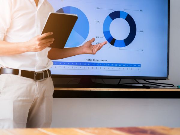 Speaker man talking to audience giving a lecture and holding tablet