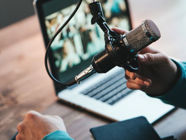 A man host streaming his audio podcast using microphone and laptop