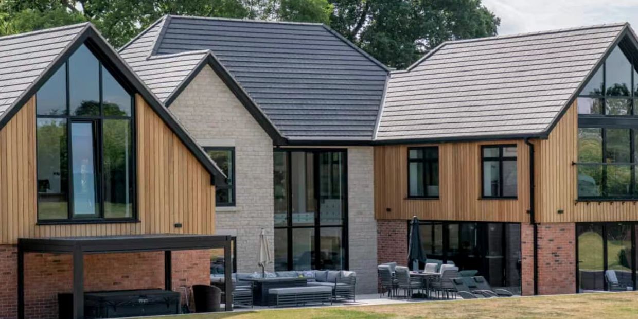 Modern house with wood, brick, and large windows in a green setting.