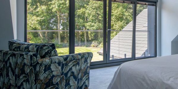 Modern bedroom with large glass windows overlooking a green garden.