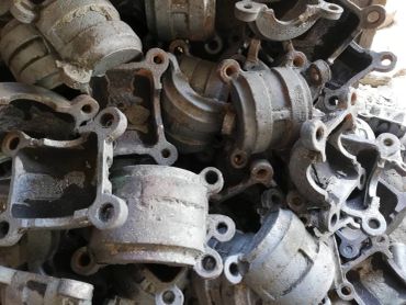 A pile of old, rusty metal mechanical parts with mounting holes.