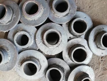 Stack of rough metal castings with circular openings.