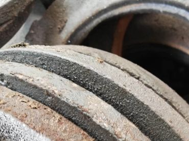 Close-up of a rusty, dusty metal pulley system.