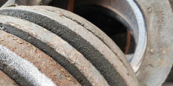 Close-up of a rusty, dusty metal pulley system.