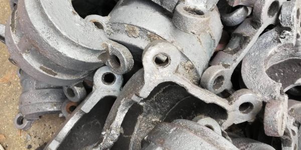 Stack of old metal castings with bolt holes, showing rust and wear.