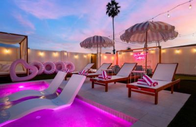 Poolside lounge chairs with pink umbrellas and sunset sky.