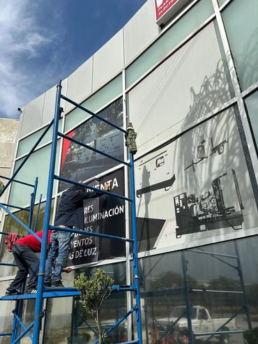 Equipo instalando vinil microperforado en los ventanales de ONIS VISA.