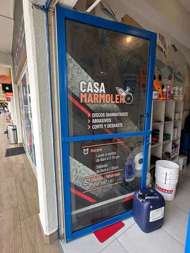 Vinil microperforado de Casa Marmolero instalado en puerta de cristal con marco azul.