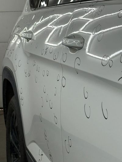 Car hood with multiple dents marked for repair.