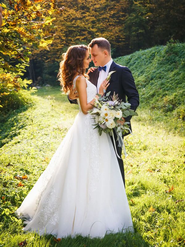 Bride and groom embracing outdoors on grass.