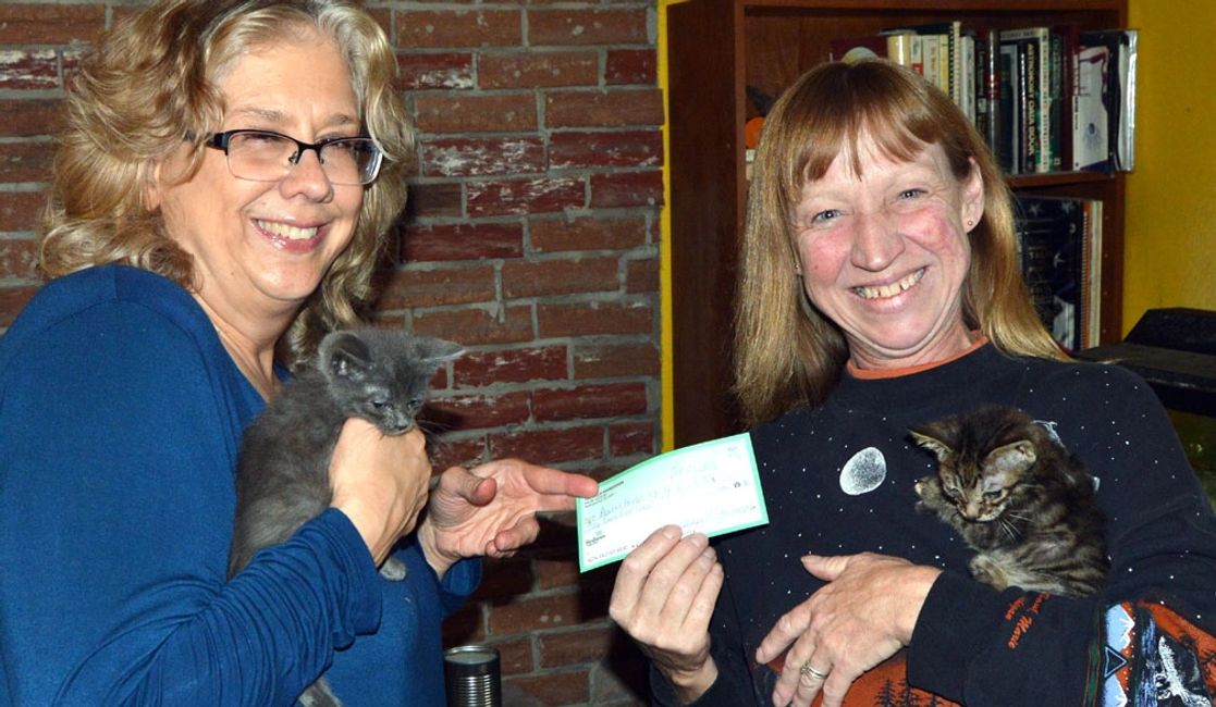 Jeanne Starmack, left, chairwoman of the Allie Foundation, gives a check for $100 to Denise Herbe of