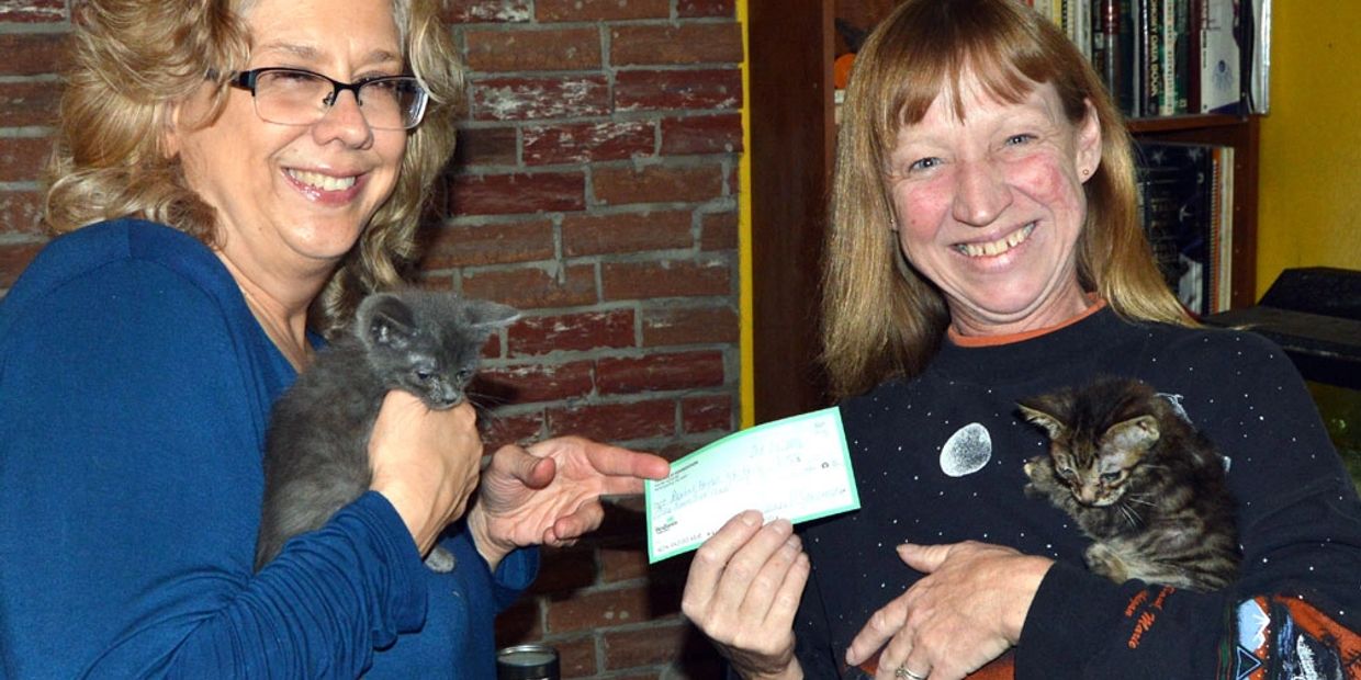 Jeanne Starmack, left, chairwoman of the Allie Foundation, gives a check for $100 to Denise Herbe of