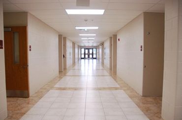 A long, empty hallway with tiled floor and multiple doors on each side.
