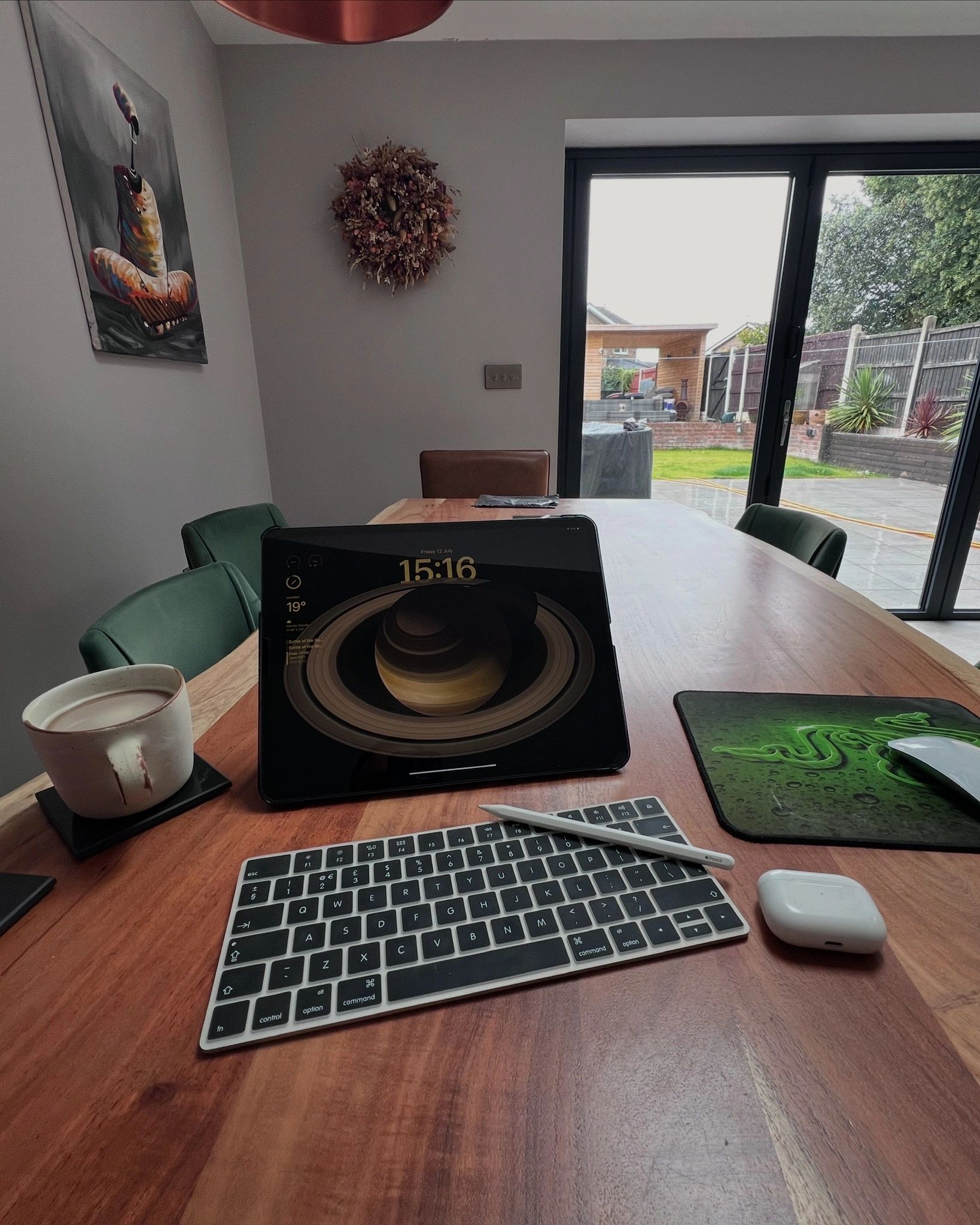 Cozy workspace with tablet, keyboard, coffee, and garden view through glass doors.