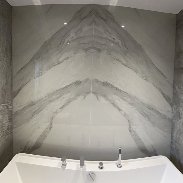 Modern bathroom with a white bathtub and elegant marble wall.