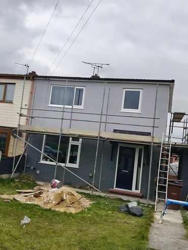 House under renovation with scaffolding and construction materials in the yard.