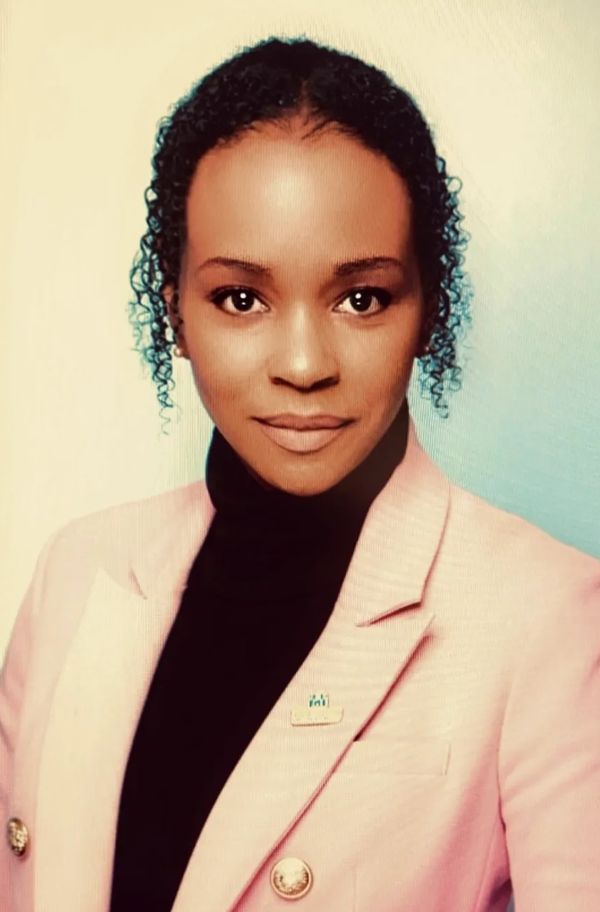 Professional woman in a pink blazer and black turtleneck, looking confidently at the camera.